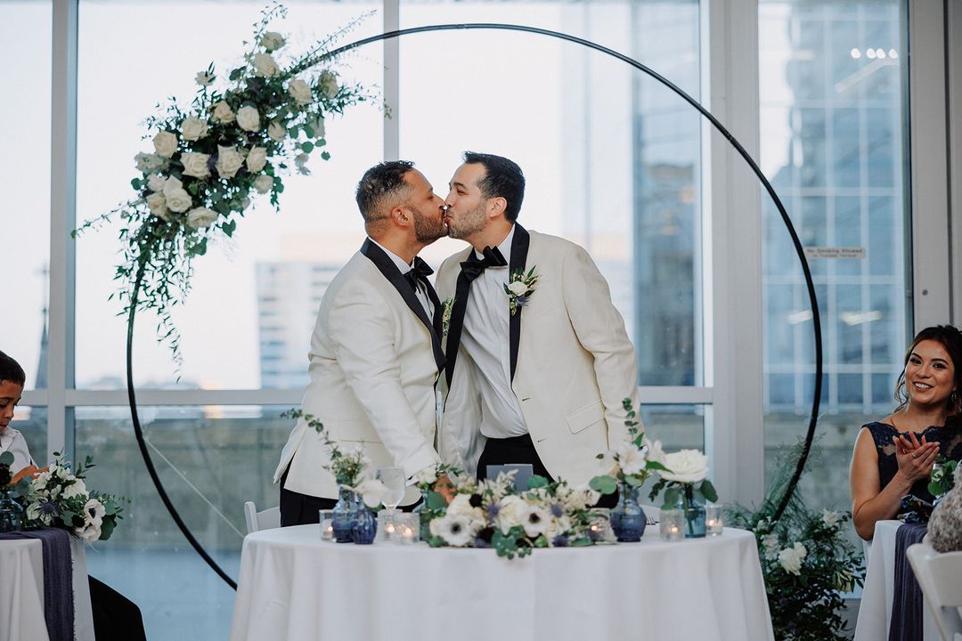 Dan and John sharing a kiss at their wedding reception